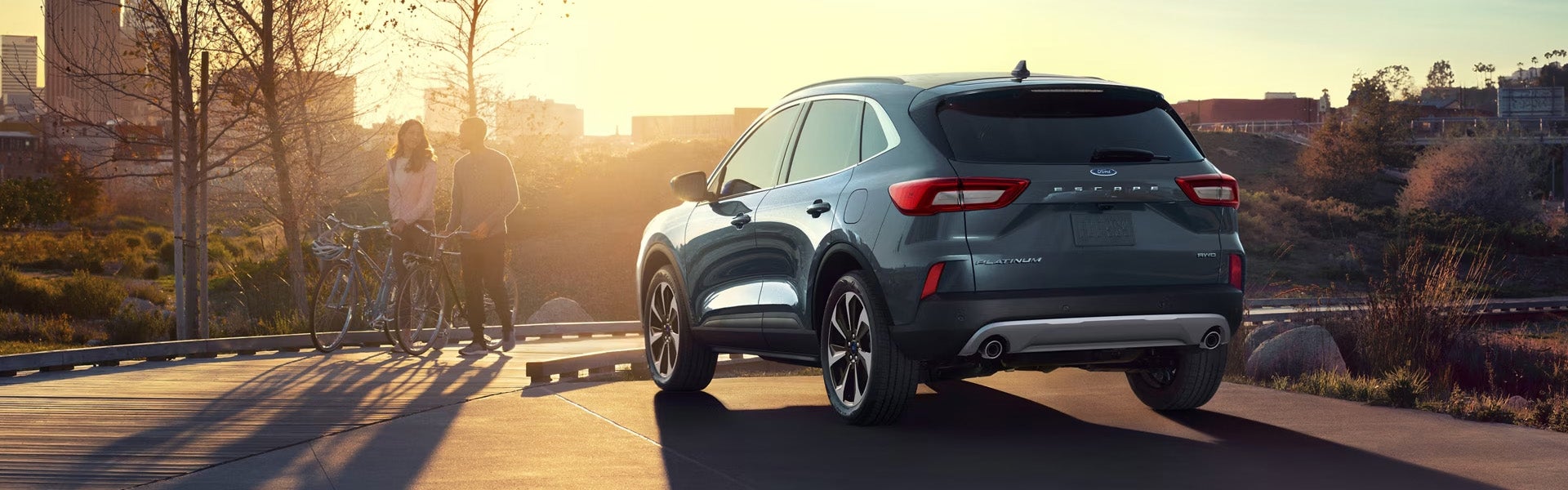 Two people standing next to a ford escape.