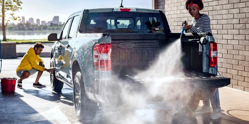 Two people washing a truck at a carwash.