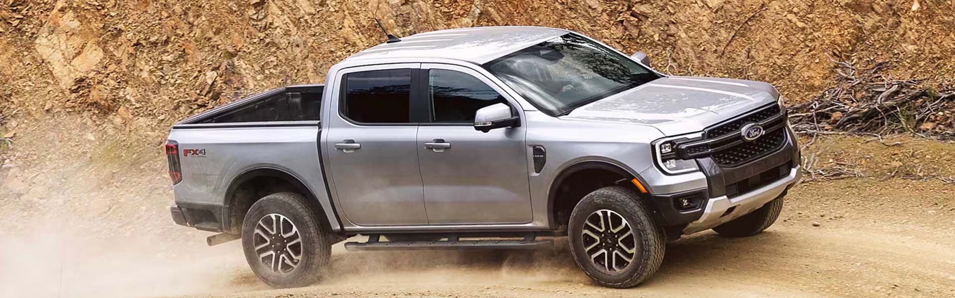 A silver truck pulling a trailer on the road.