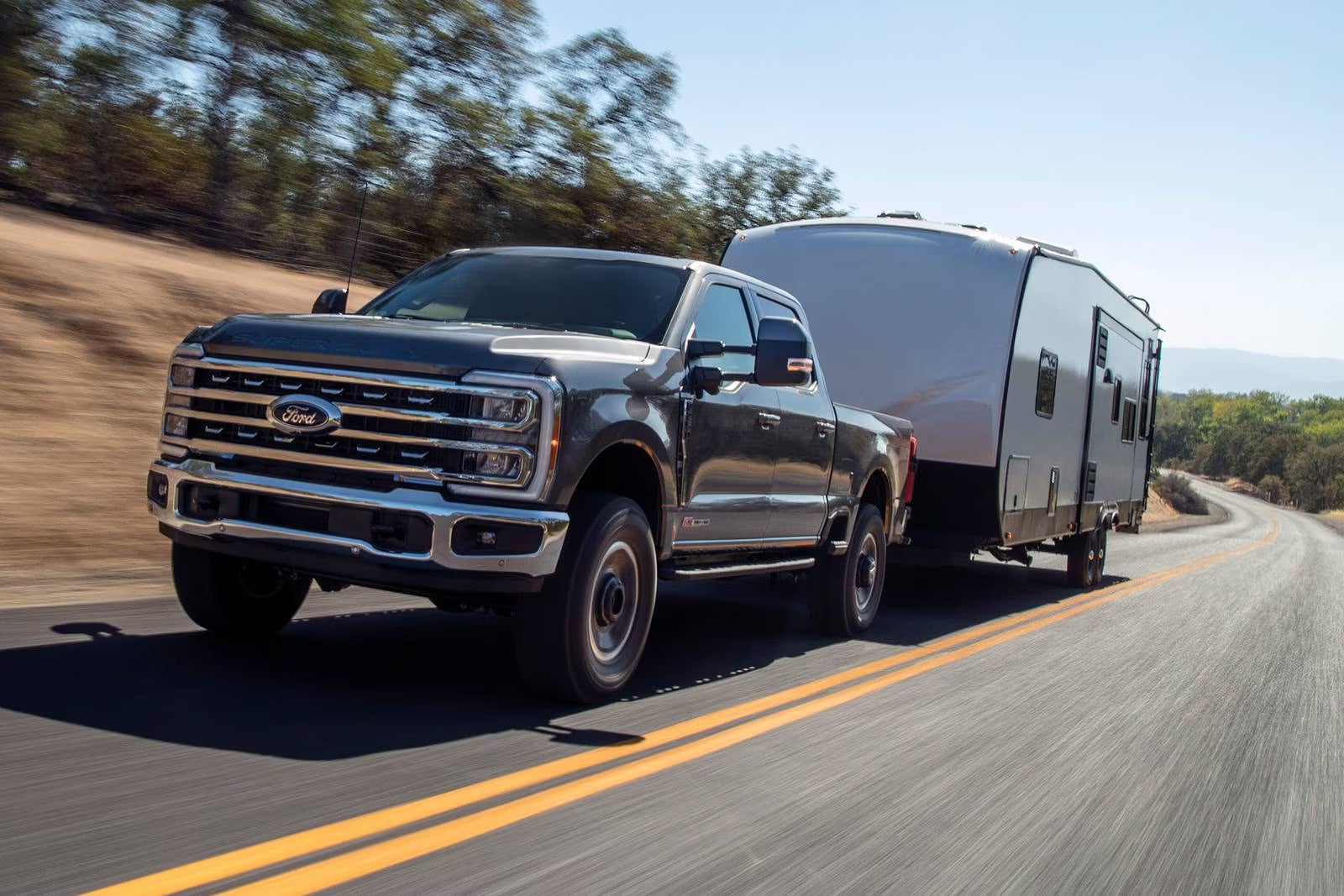 A black truck driving on the road with a trailer.