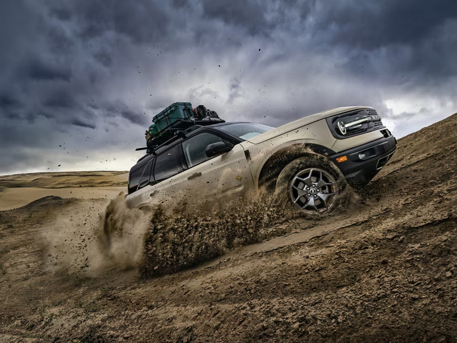 a beige suv driving uphill in the sand