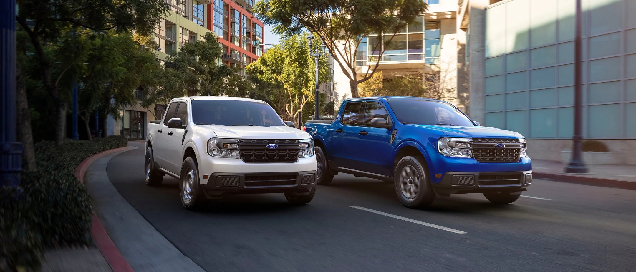 a blue and a white truck driving on the road in the city