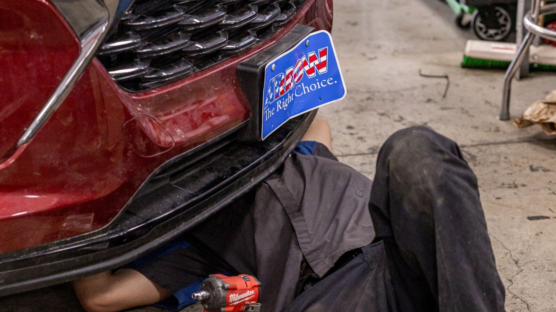 service tech underneath a red suv