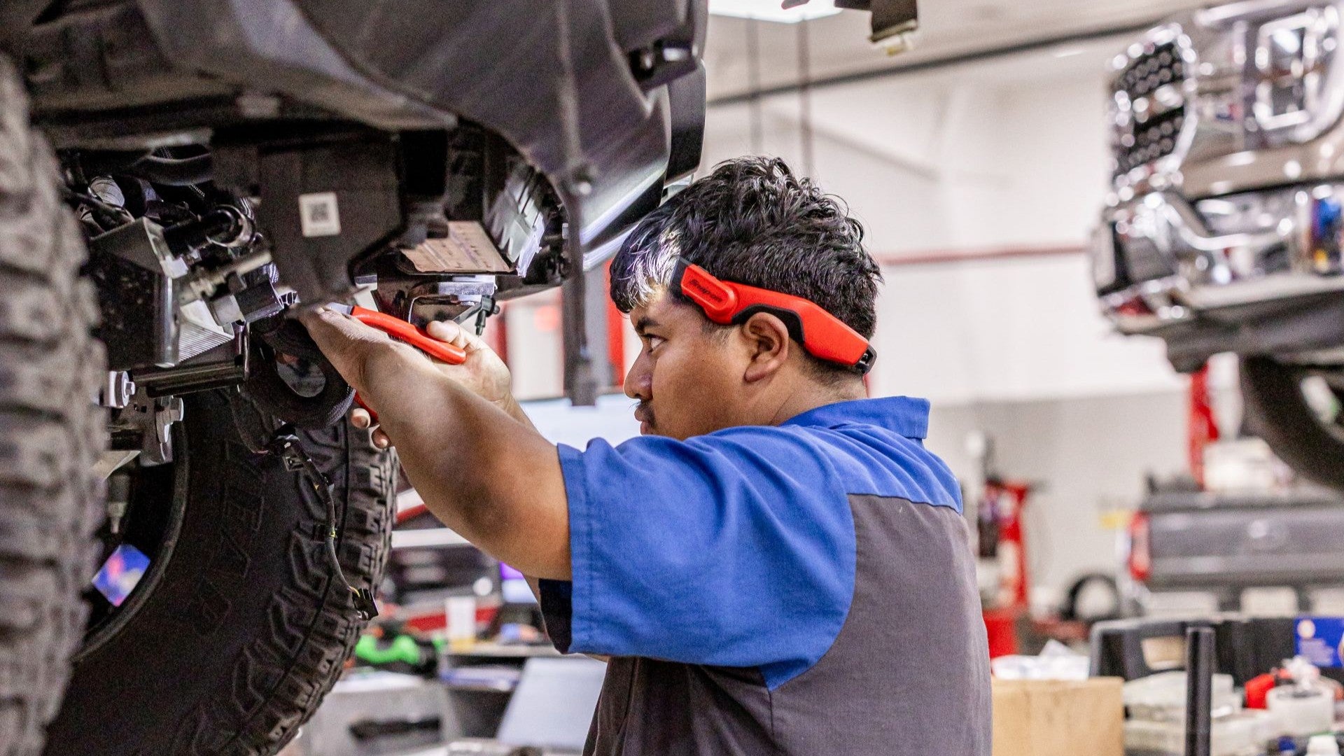 ford technician working near the tires of a vehicle on a lift