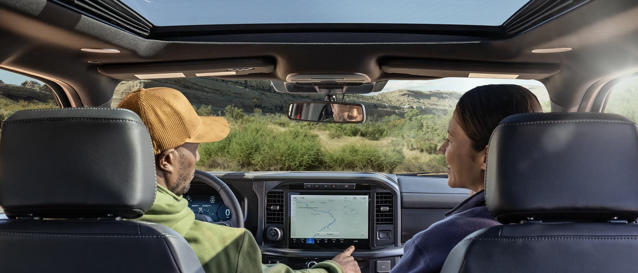 two people in the front seats using navigation with trees in front