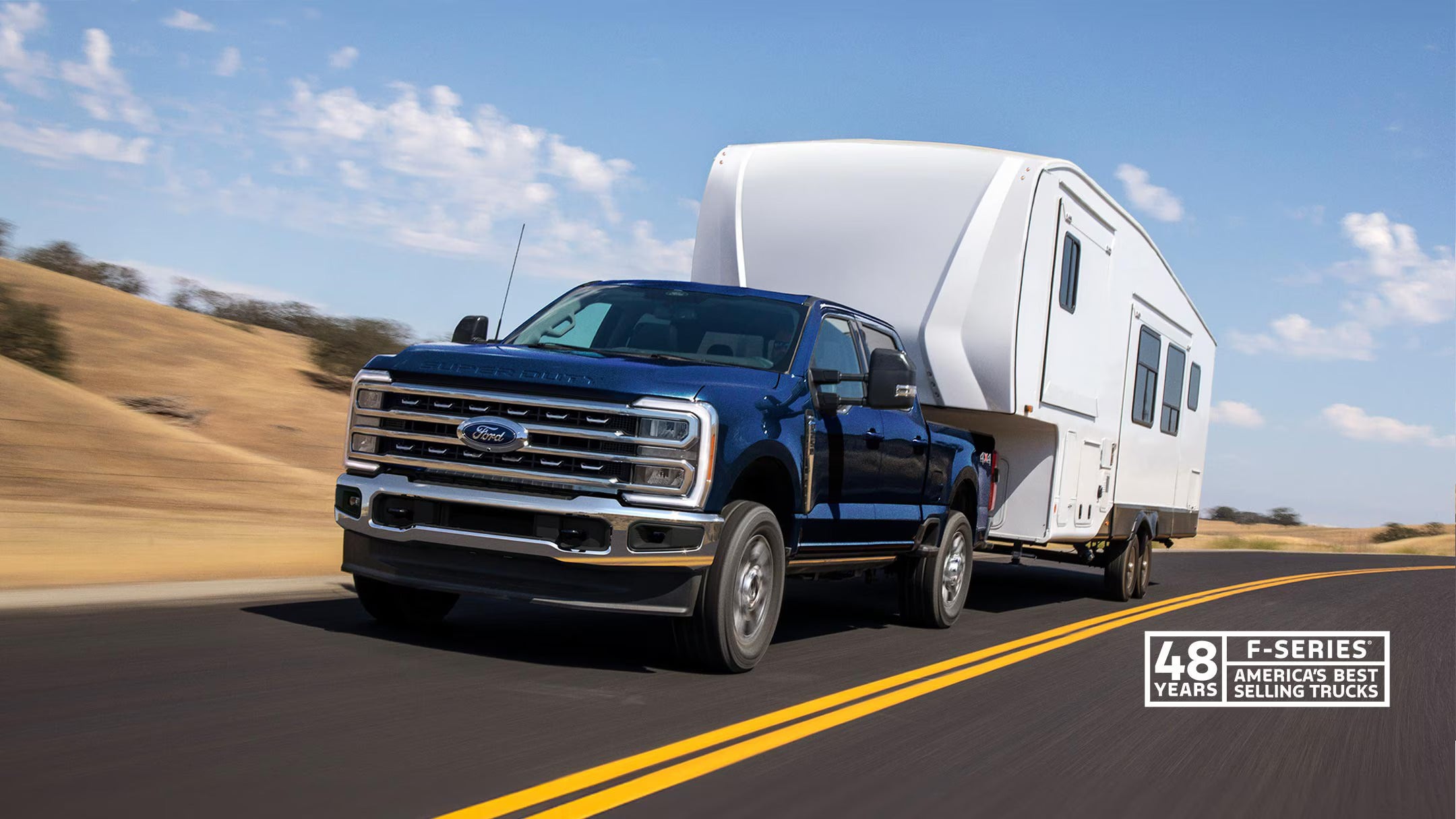 a black ford super duty truck hauling a white camper trailer with a desert background