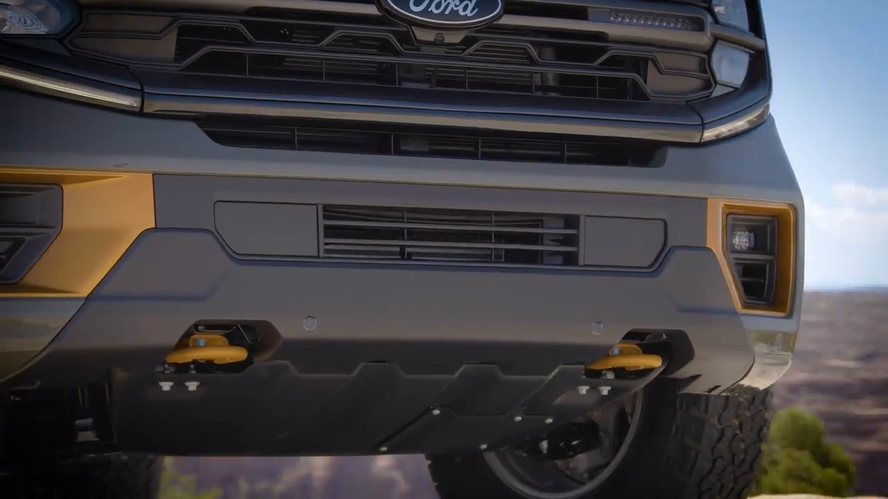 Close-up of the underbody of a Ford Expedition showing protective skid plates and front tow hooks.