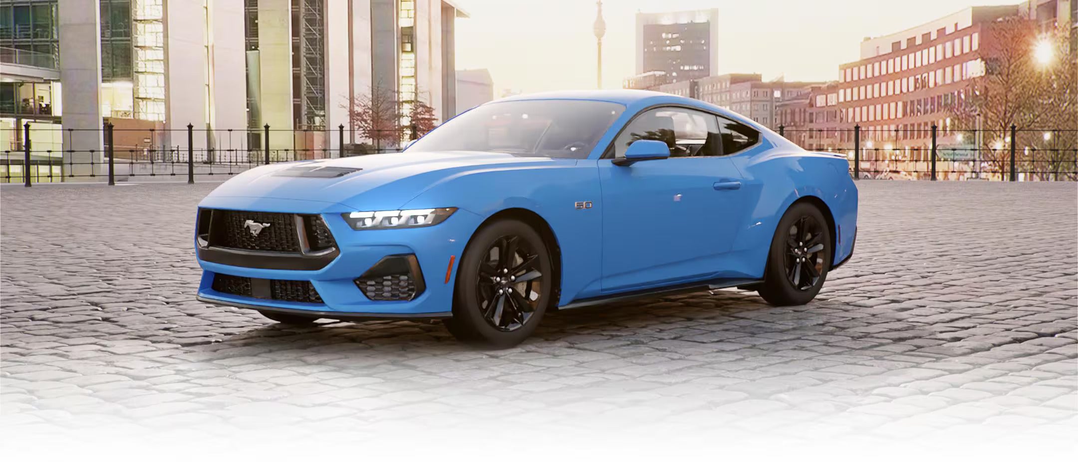 Side view of a blue 2025 Ford Mustang GT parked in a modern urban setting.