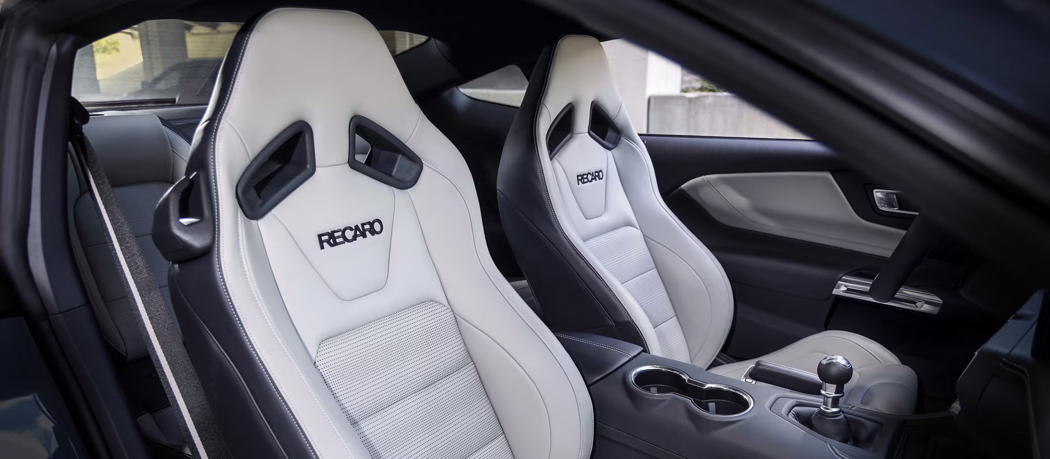Interior of the 2025 Ford Mustang featuring Recaro seats with white and black accents, offering a sporty and comfortable design.