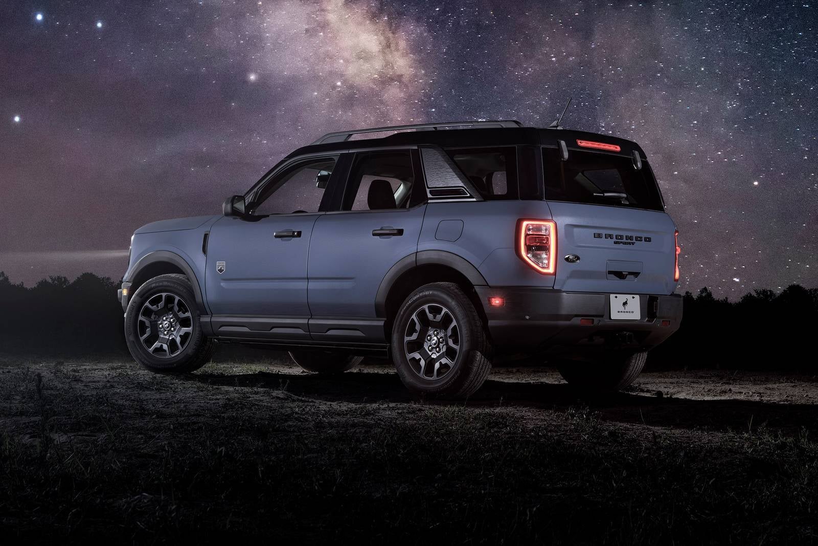 A gray bronco sport sitting parked at night time.