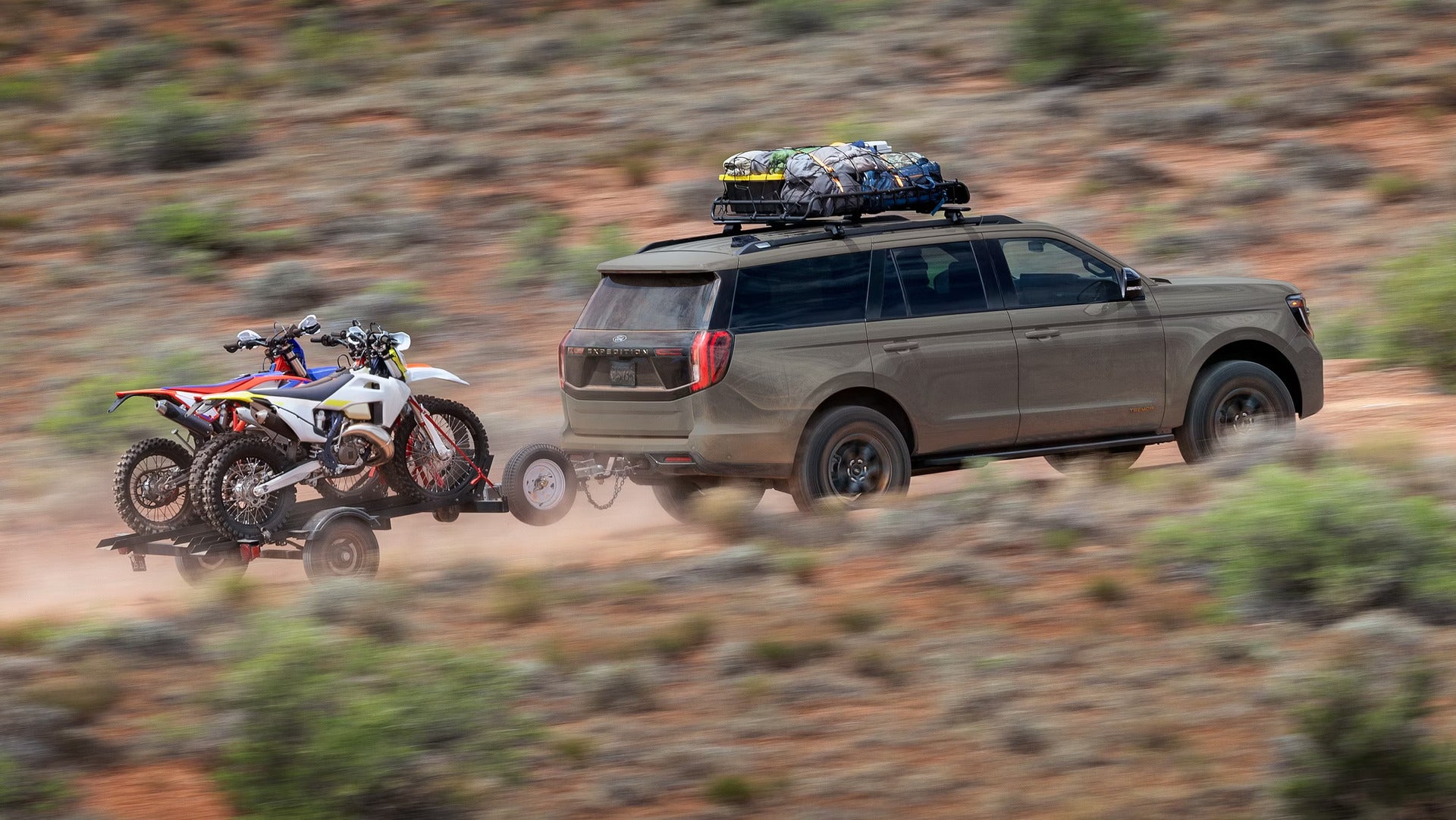 hauling dirt bikes in the desert while driving a 2026 ford expedition on a dirt path