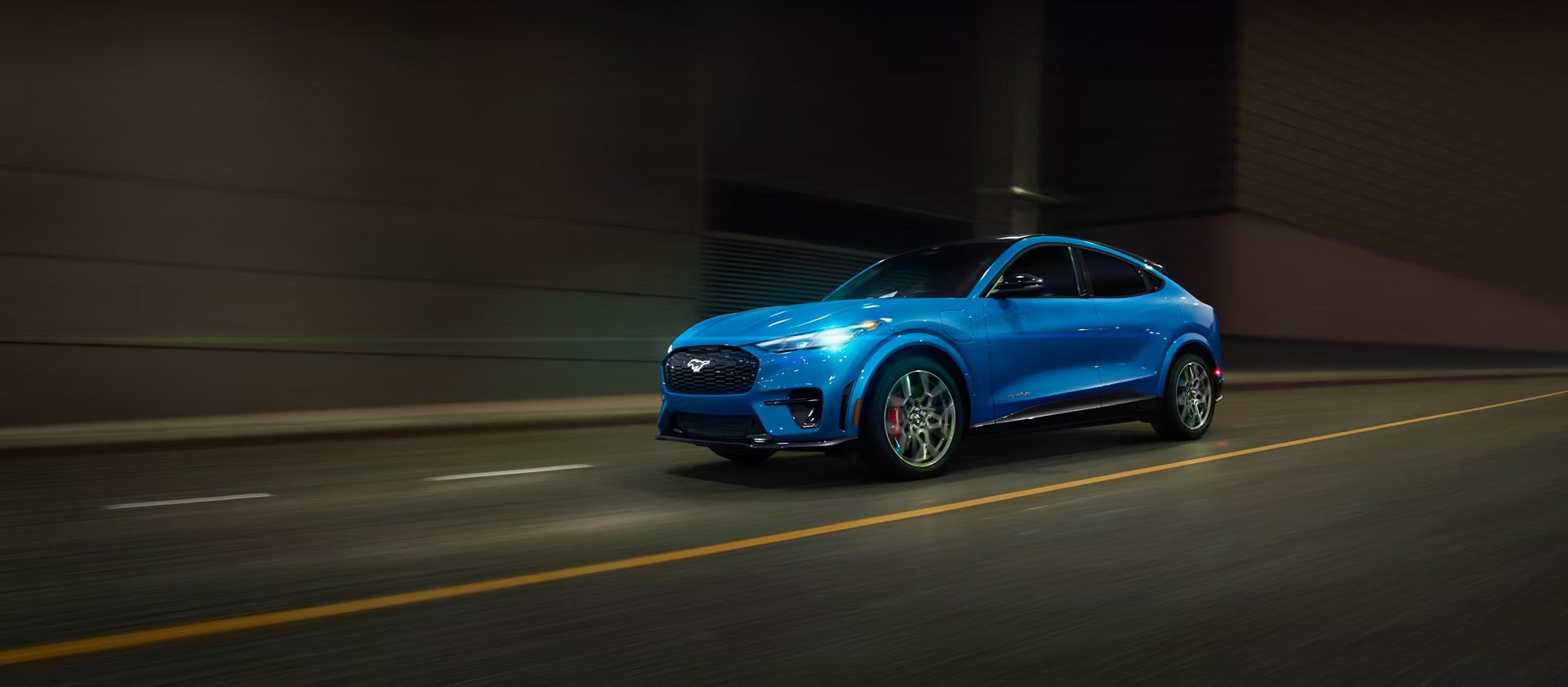 A blue mustang mach-e driving on the road.