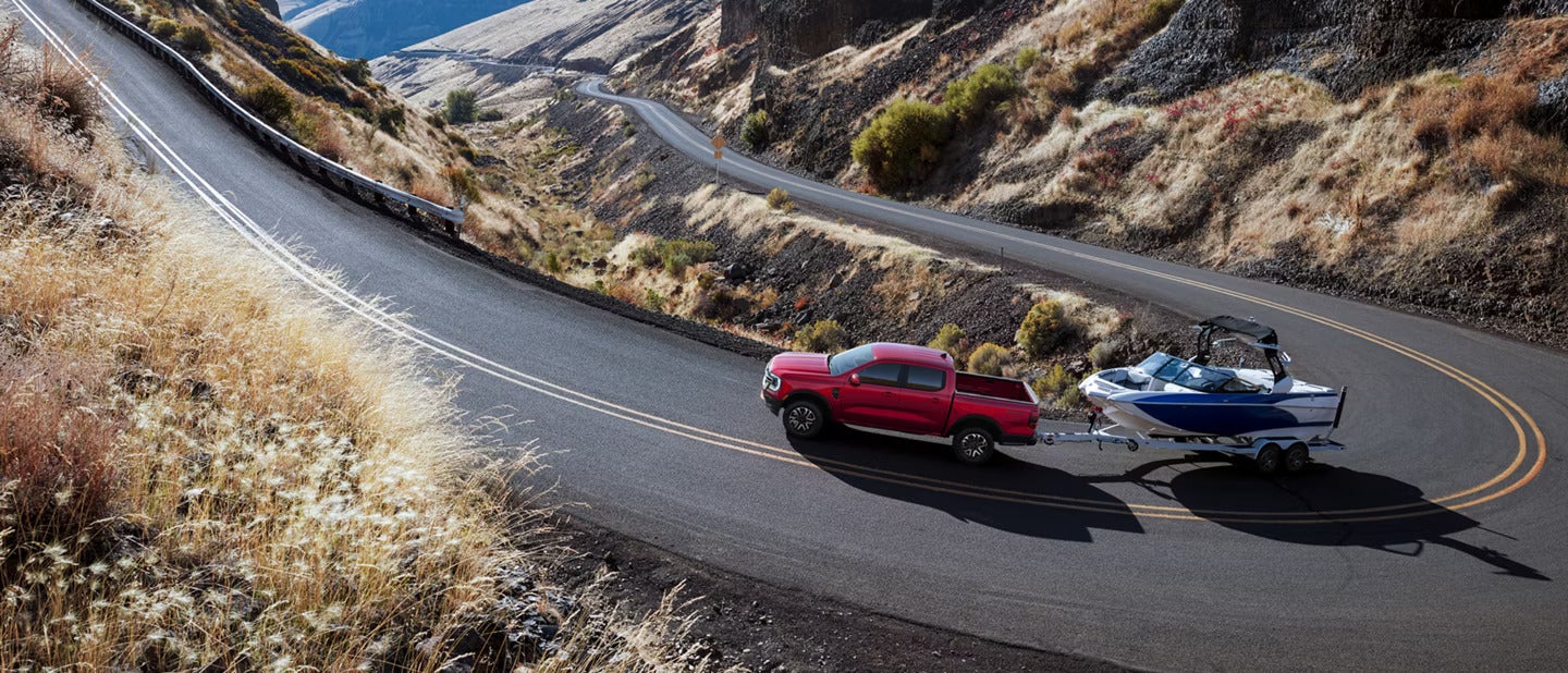 A red truck pullinga boat on the road.
